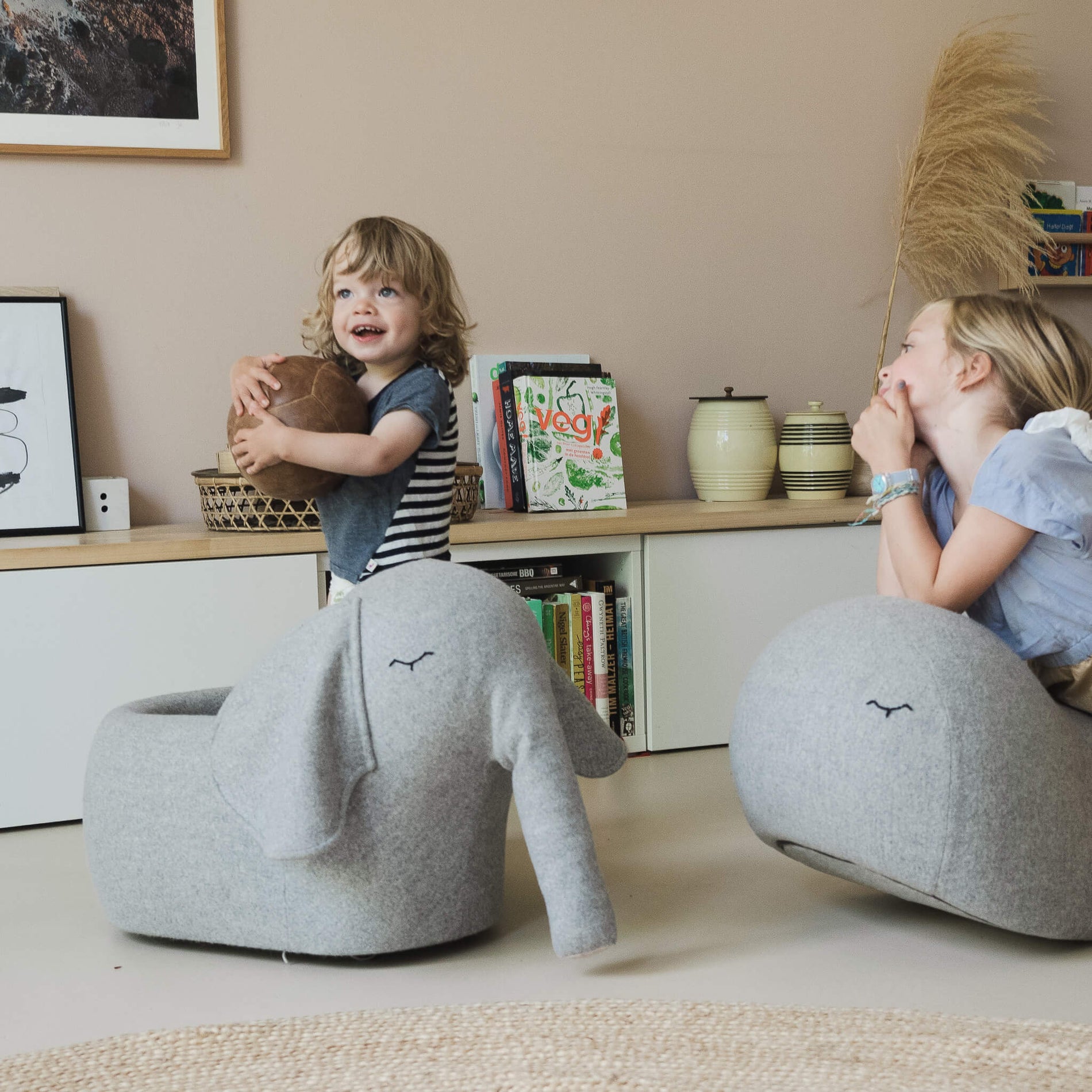 Junge spielt mit Roll-Elefant und Schwester auf Schaukel-Wal schaut zu